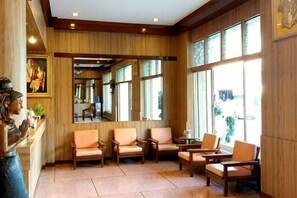 A lobby with wooden paneling, large windows, and seating arrangements. - Suriwong Chumphon Hotel (Chumphon)