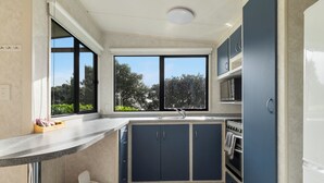Een moderne keuken met een groot raam, een ingebouwde oven en donkerblauwe kastjes.