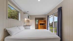 Een slaapkamer met een groot bed, een bureau met stoel, een stapelbed en uitzicht op de omgeving.