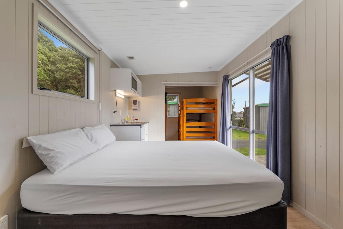 Un dormitorio con una cama grande, un escritorio con silla, una litera y vistas al exterior.