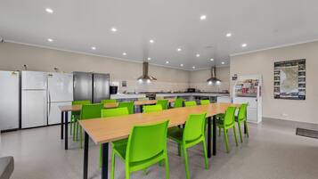 Una cocina moderna con electrodomésticos de acero inoxidable, una larga mesa de madera con sillas verdes y un mapa en la pared.