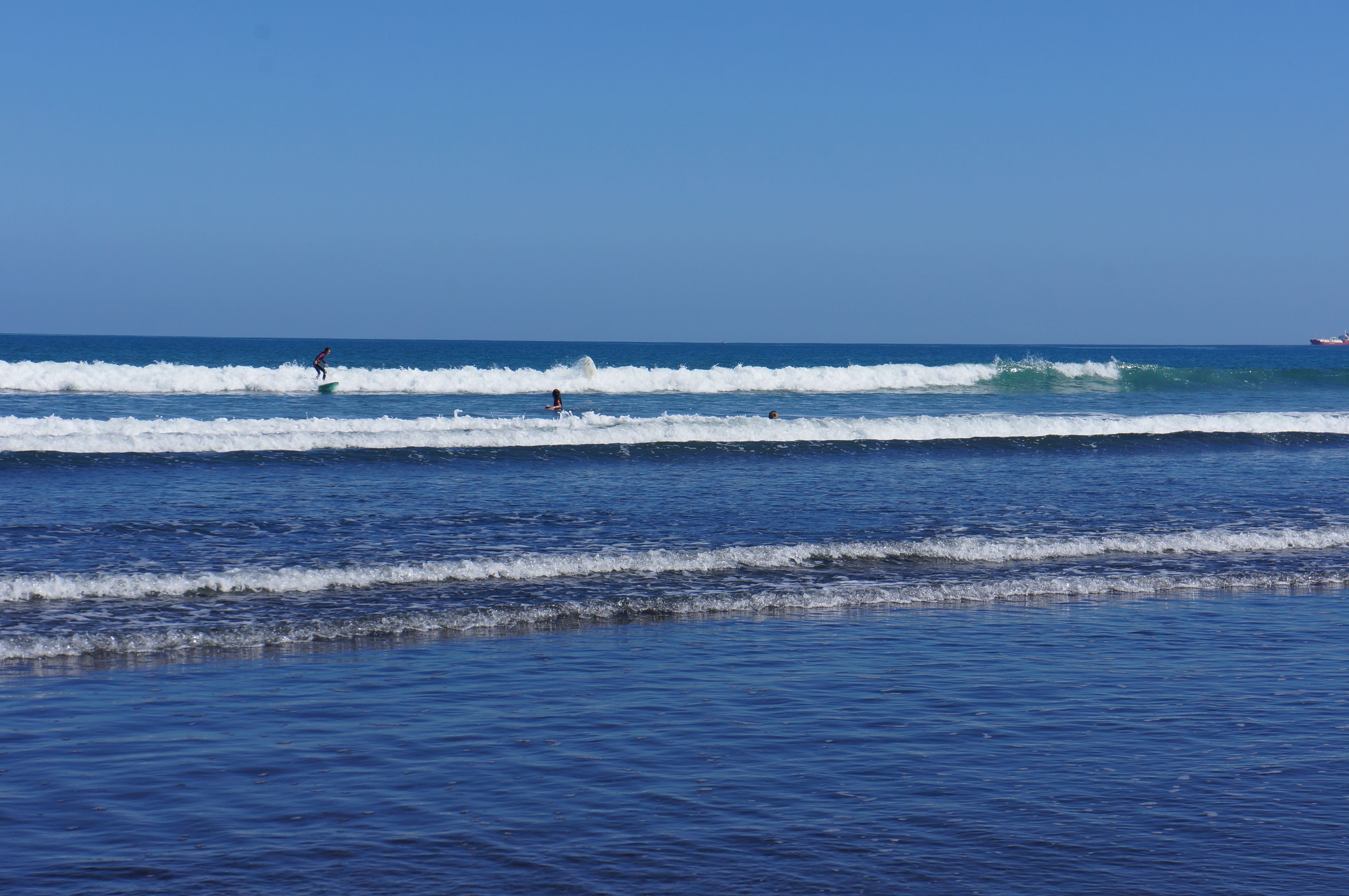 A beach with waves and a clear sky.
