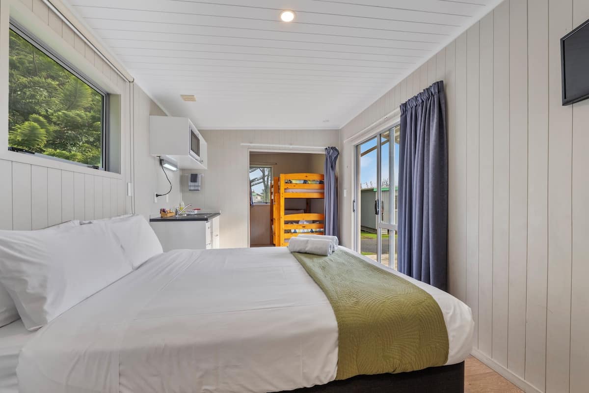 Habitación de hotel con una cama grande, un escritorio con computadora y vistas al exterior a través de una ventana.