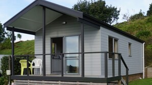 Een gelijkvloers, modern huis met een overdekte veranda, een klein terras en een gazon.