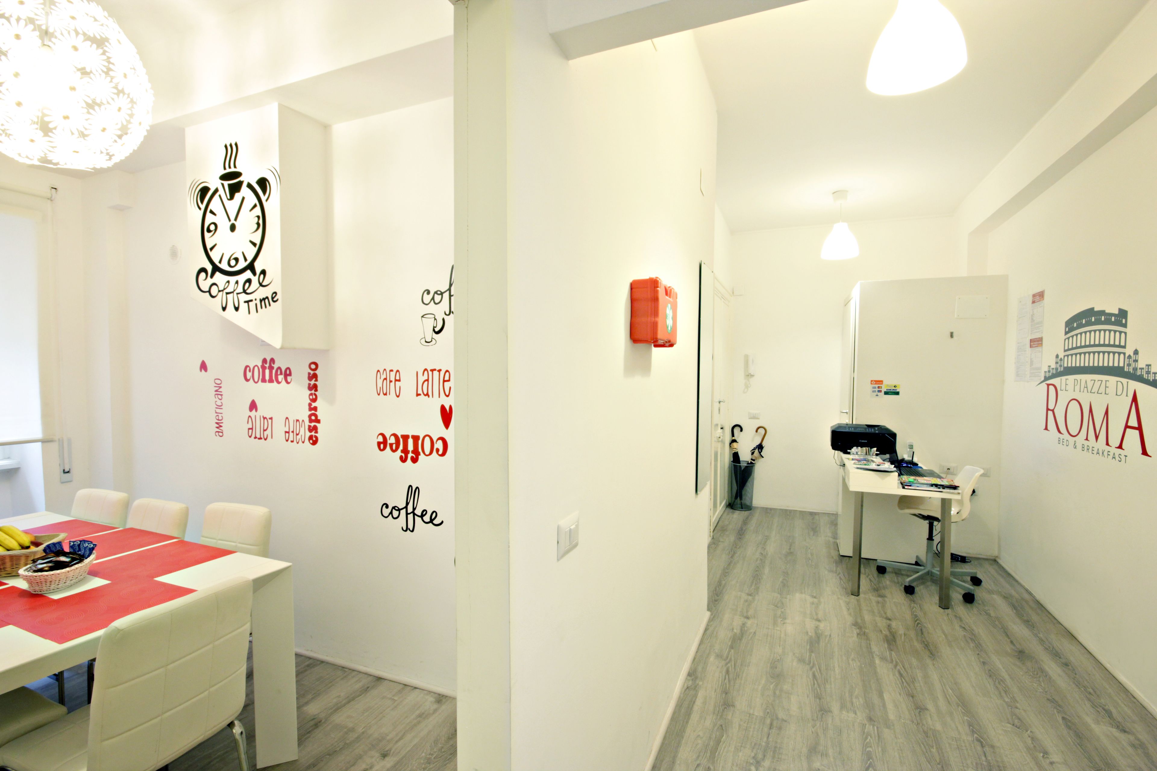A modern hotel room with a dining area, a kitchenette, and a bathroom.