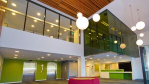 A modern interior with a reception desk, two elevators, and a red circular seating area. - Deakin Residential Services (Burwood)