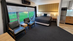 Una camera d'albergo moderna con un letto grande, una scrivania, due sedie, una TV e un angolo cottura.