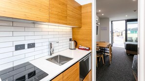 Una cucina moderna con mobili in legno, piastrelle bianche, lavastoviglie integrata e un'area pranzo con tavolo e sedie.