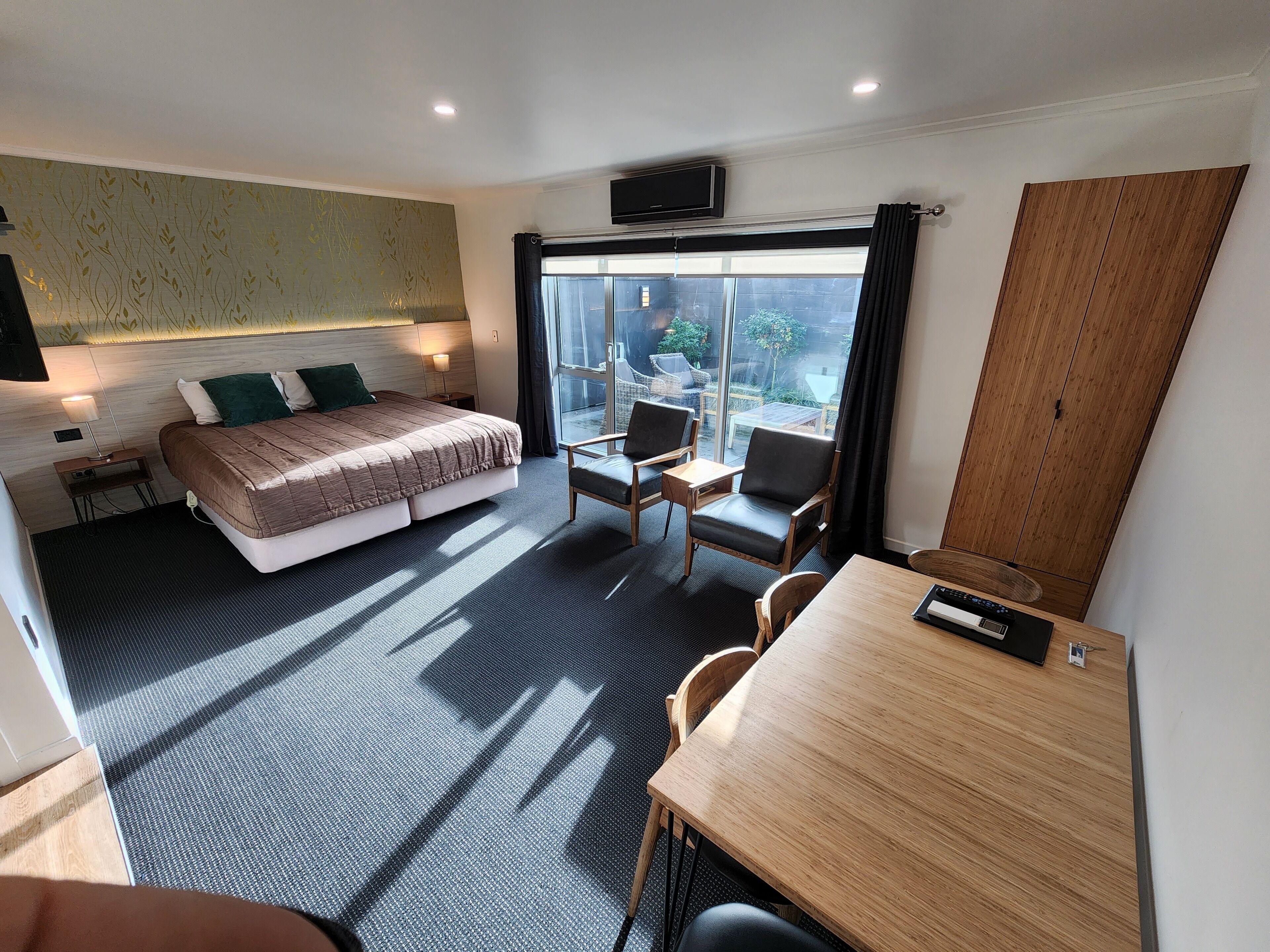 Ein modernes Hotelzimmer mit einem großen Bett, einem Schreibtisch und einem Balkon mit Blick.