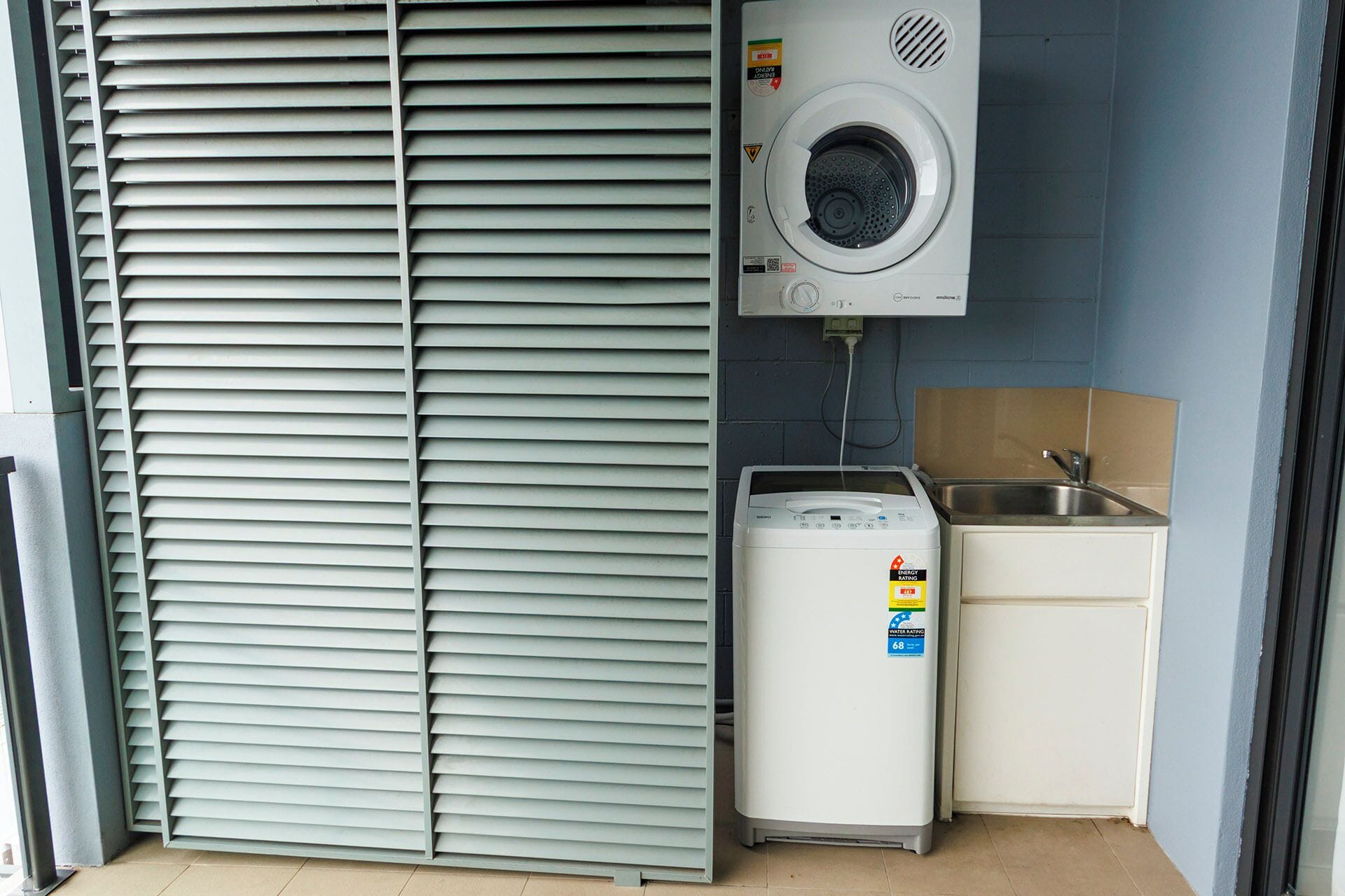 A compact laundry room with a washing machine, a dryer, and a sink.