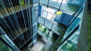 A multi-level indoor space with glass railings, metal staircases, and potted plants. - Atrio Apartments (Fortitude Valley)