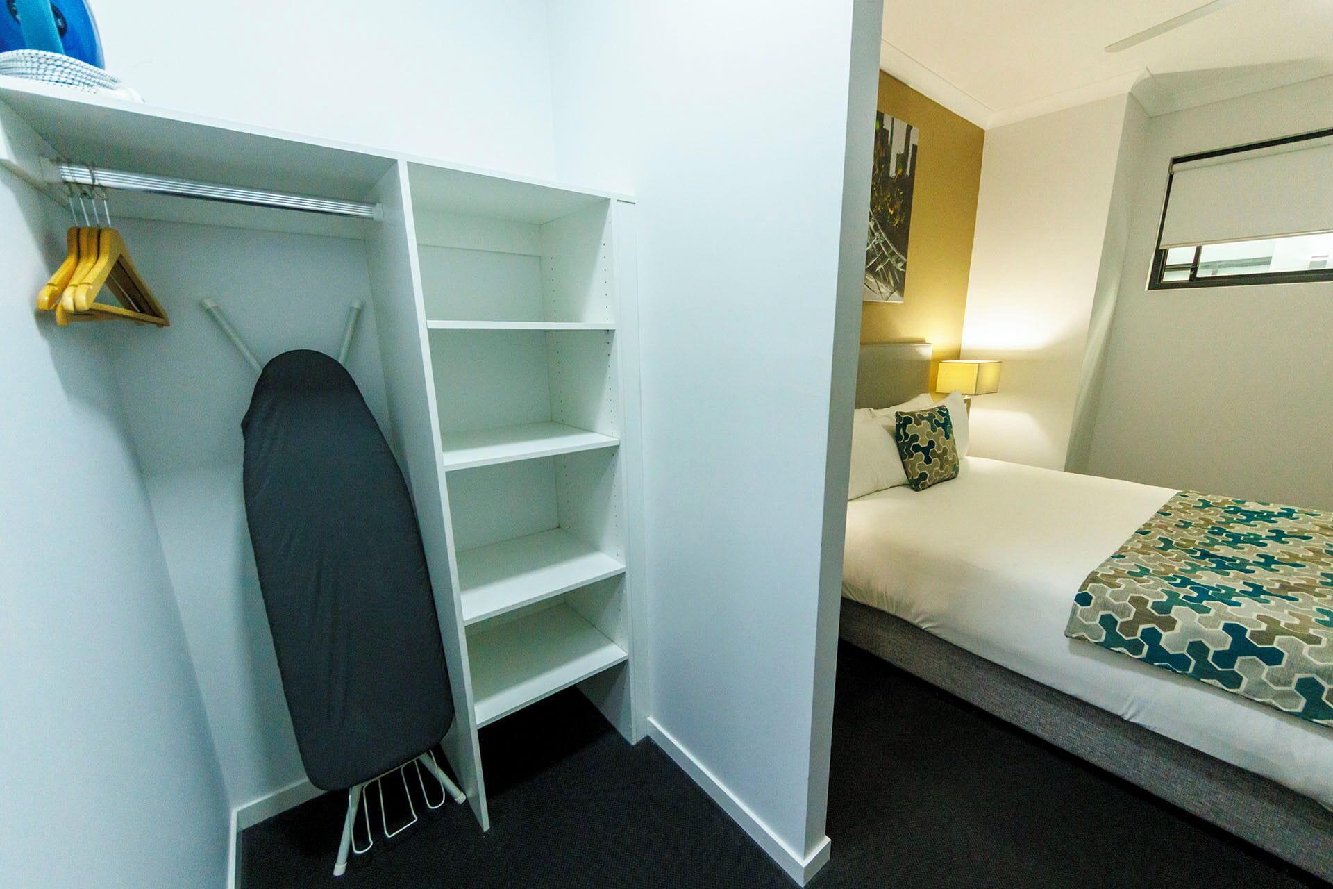 A hotel room with a bed, a wardrobe, and a hanging garment rack.