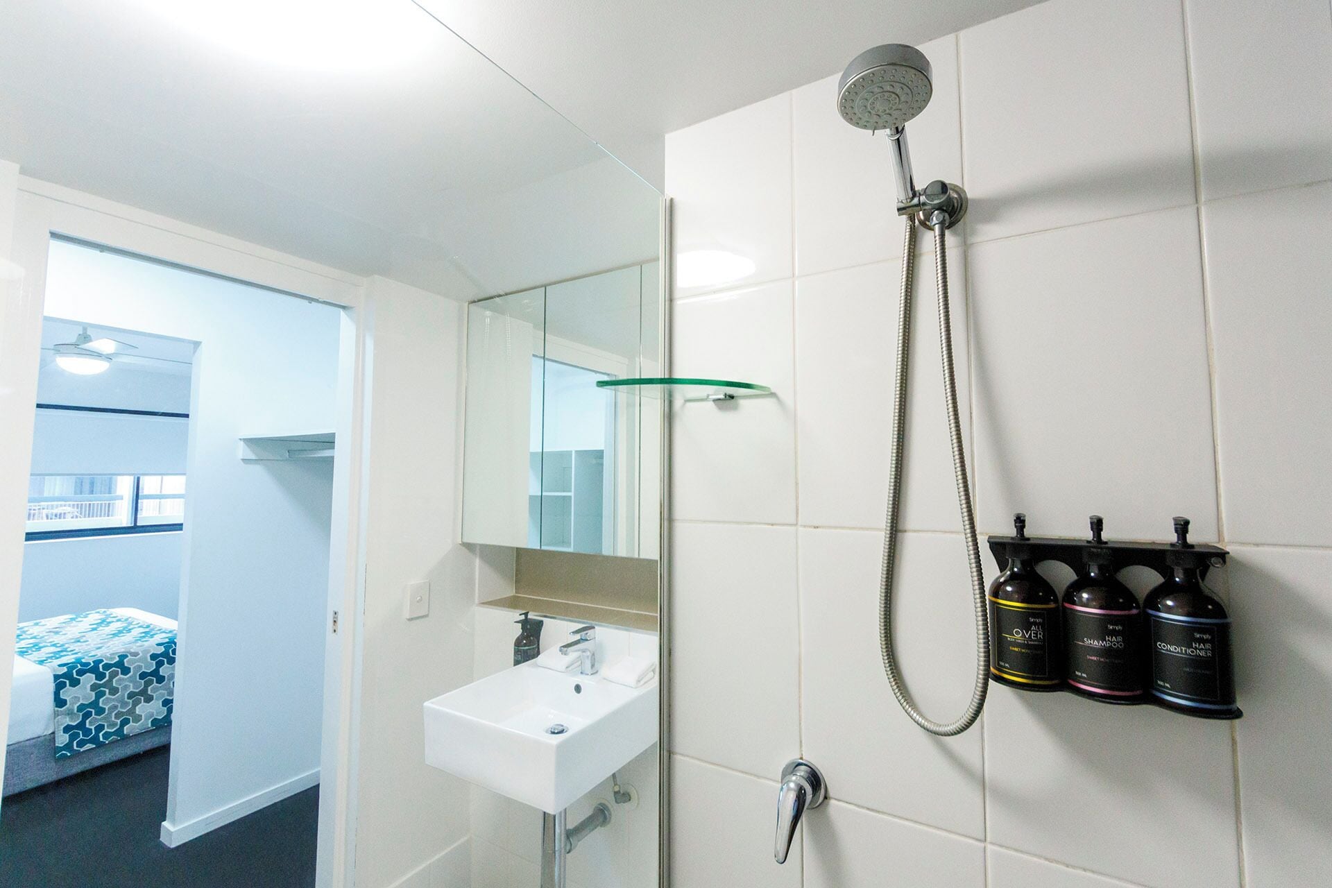 A bathroom with a shower, sink, and toiletries.
