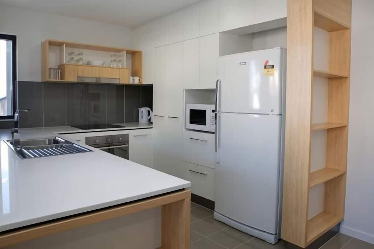 A modern kitchen with a white countertop, a built-in microwave, and a stainless steel refrigerator.