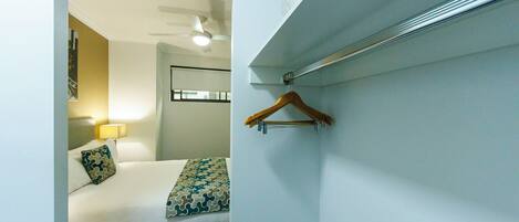 A hotel room with a bed, a hanging wooden hanger, and a ceiling fan.