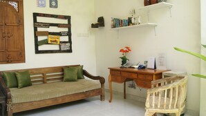 Una habitación acogedora con un sofá de madera, un escritorio con teléfono y calendario, y una silla de madera.