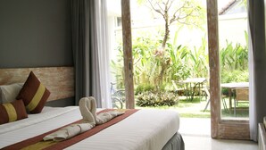 Habitación de hotel con cama, ventana y vistas a un jardín y zona de estar al aire libre.