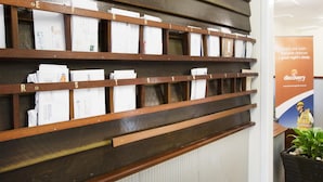 A wooden shelf with labeled compartments containing white boxes. - Discovery Parks - Mount Isa (Winston)