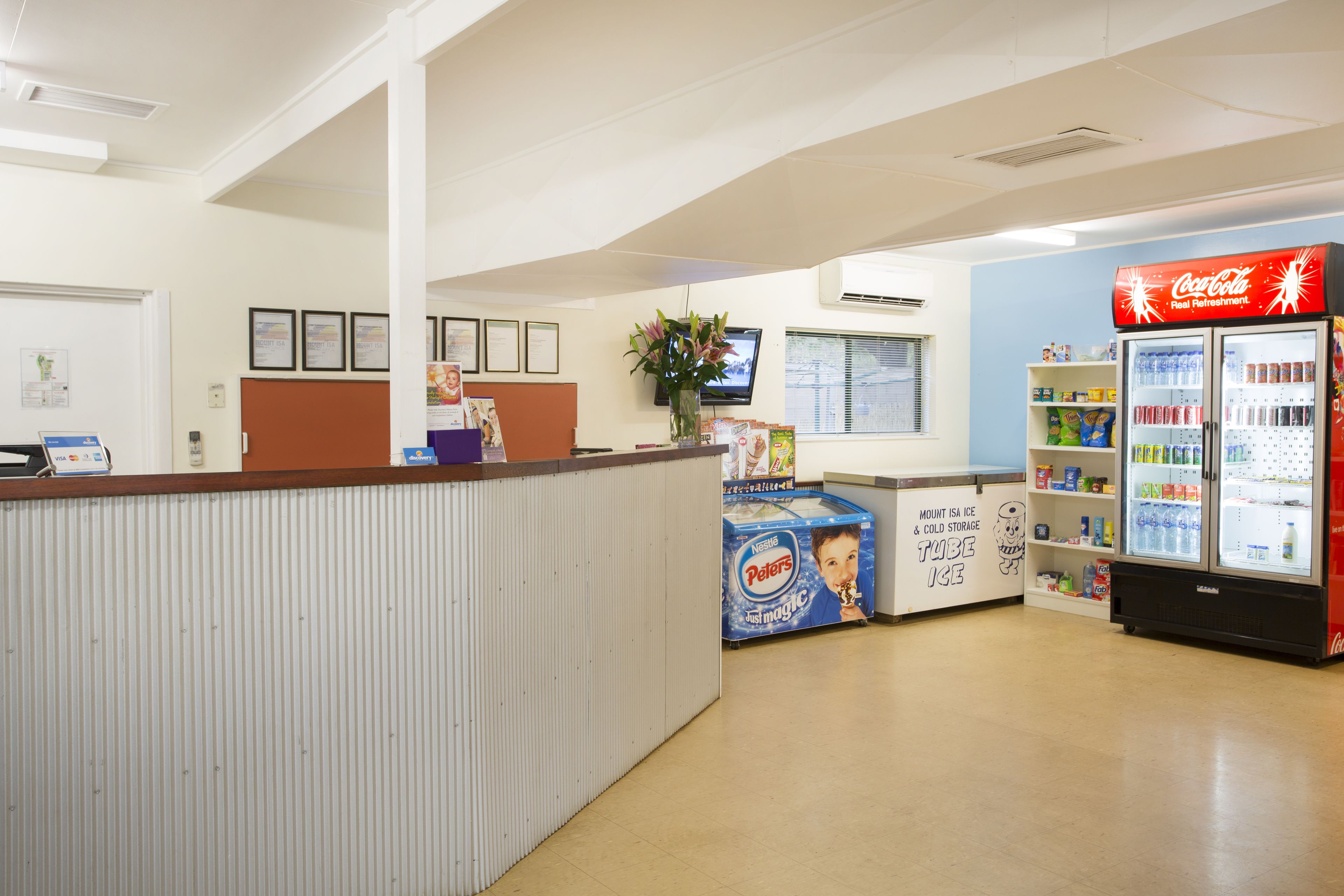 A reception area with a Coca-Cola refrigerator, a counter with a flower vase, and a display of children's products.