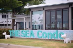 A building with a sign reading "THESEA Condo" and a large glass window. - The Sea Condominium (Sam Roi Yot)