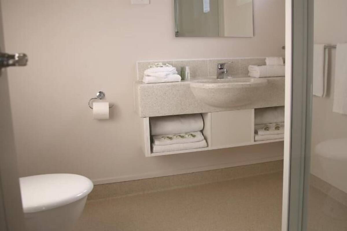Un baño con inodoro, lavamanos y espacio para toallas.