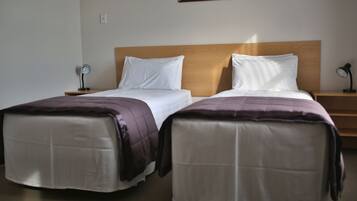 A hotel room with two beds, a wooden headboard, and bedside lamps.