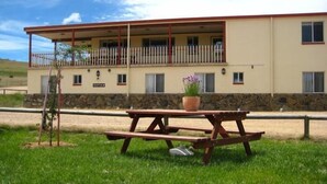 A building with a reception area, a balcony, and a picnic table with a potted plant. - JE Resort (Avonside)