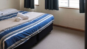 A bedroom with a bed, a window, and curtains. - JE Resort (Avonside)