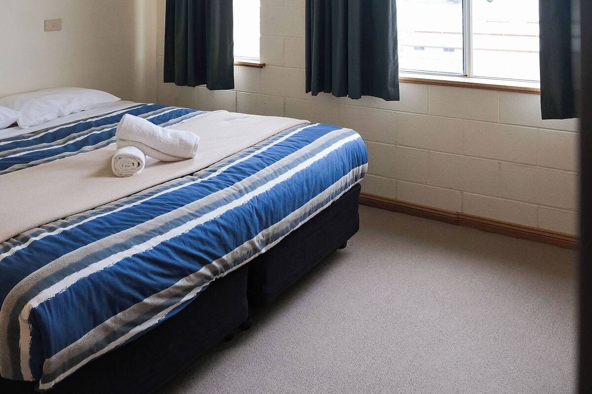 Een slaapkamer met een bed, een raam en gordijnen.
