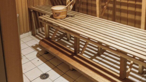 A wooden sauna with benches and a small bucket. - JE Resort (Avonside)