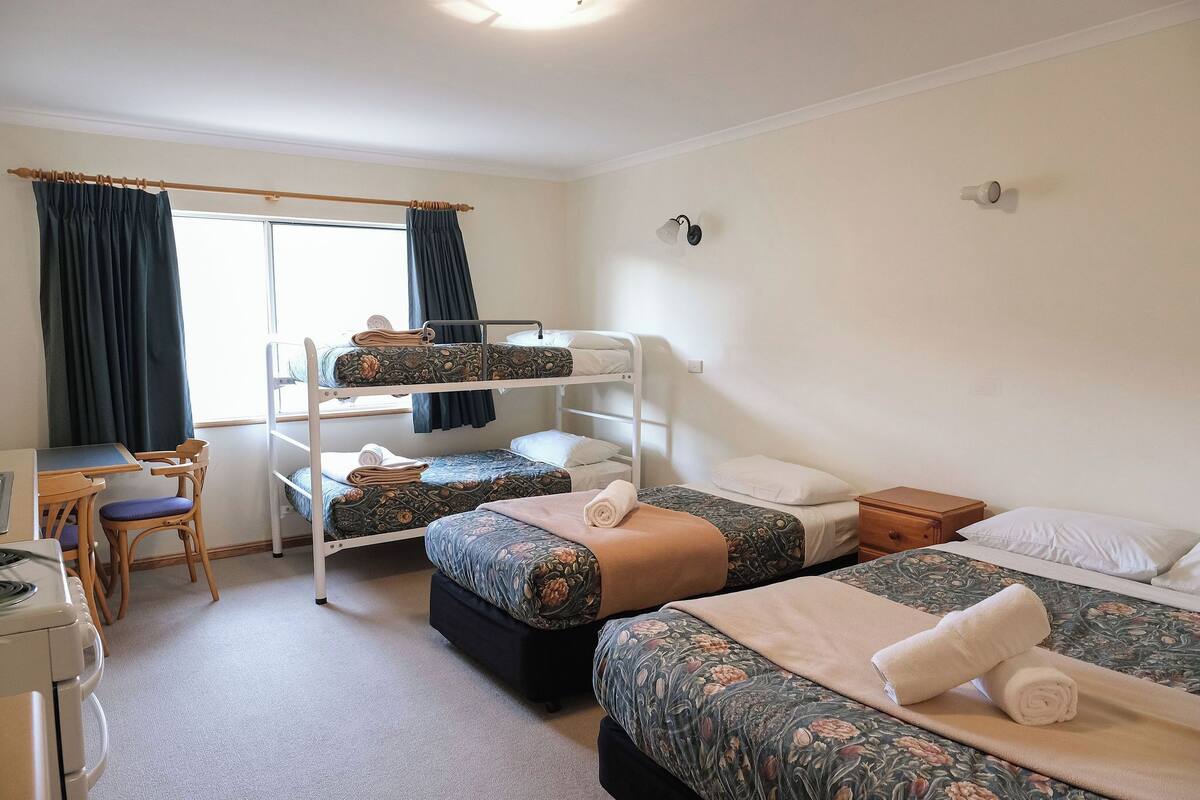 Een kamer met stapelbedden, een bureau en een stoel.