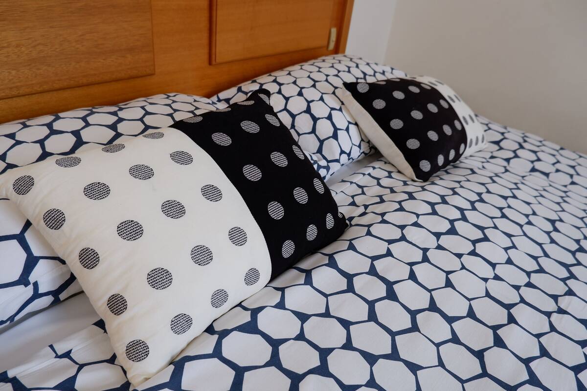 A bed with a geometric patterned bedspread and pillows with a polka dot design.