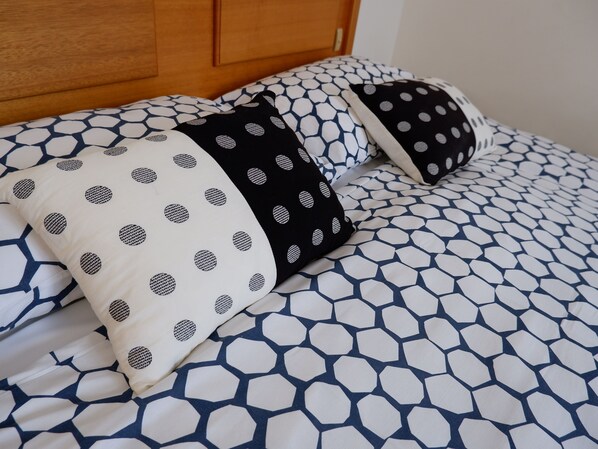 A bed with a geometric patterned bedspread and pillows with a polka dot design. - Alpenhorn (Thredbo)