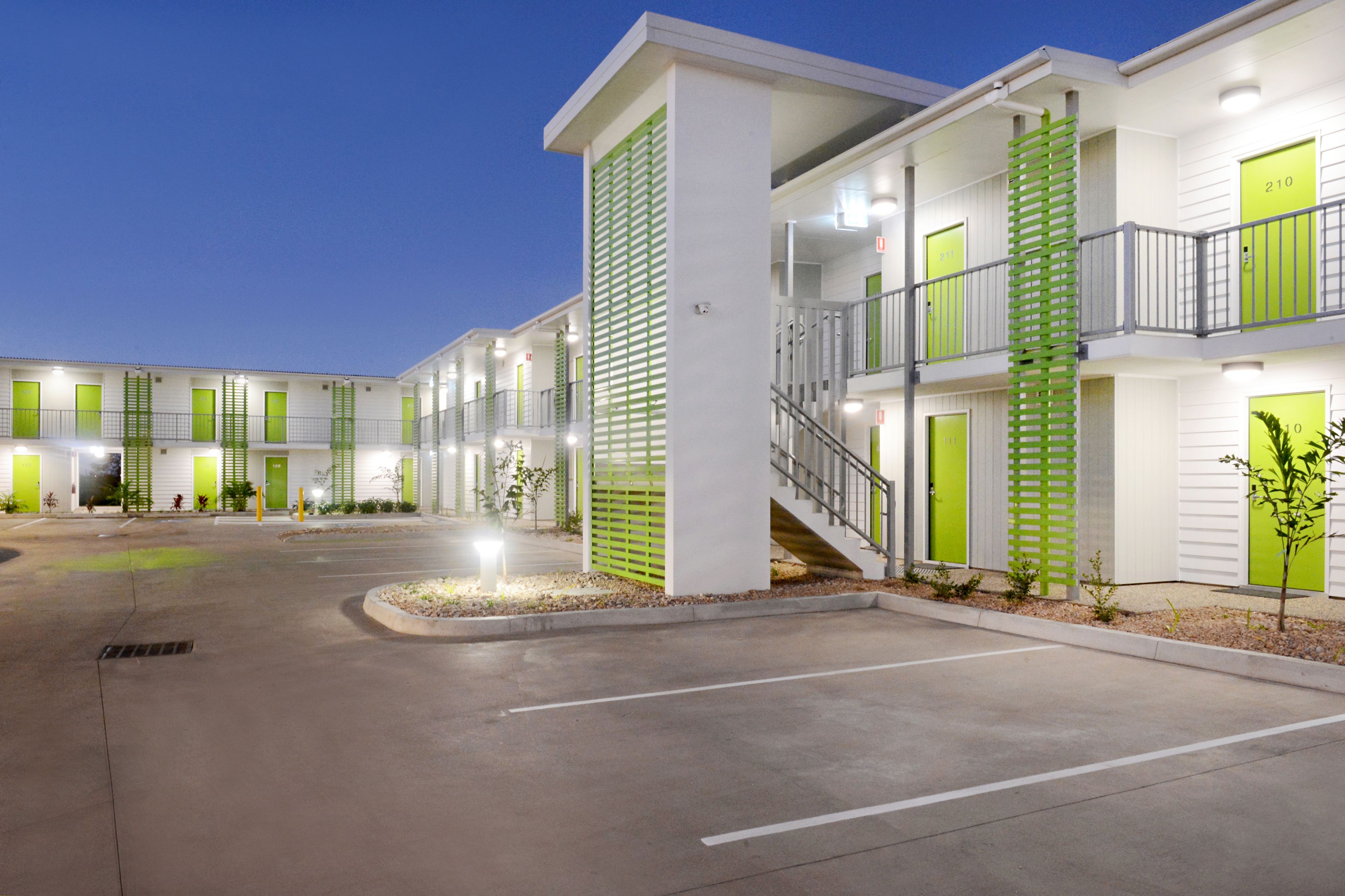 Een motel met meerdere verdiepingen, groene deuren en een centrale trap.