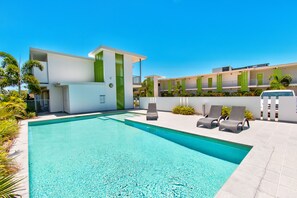 A modern hotel with a swimming pool, outdoor seating, and a clear blue sky. - Mackay Oceanside Central Hotel (East Mackay)