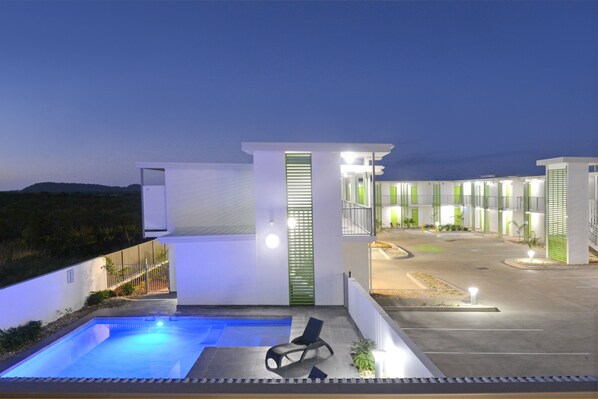 A modern hotel with a swimming pool, outdoor seating, and a well-lit entrance. - Mackay Oceanside Central Hotel (East Mackay)