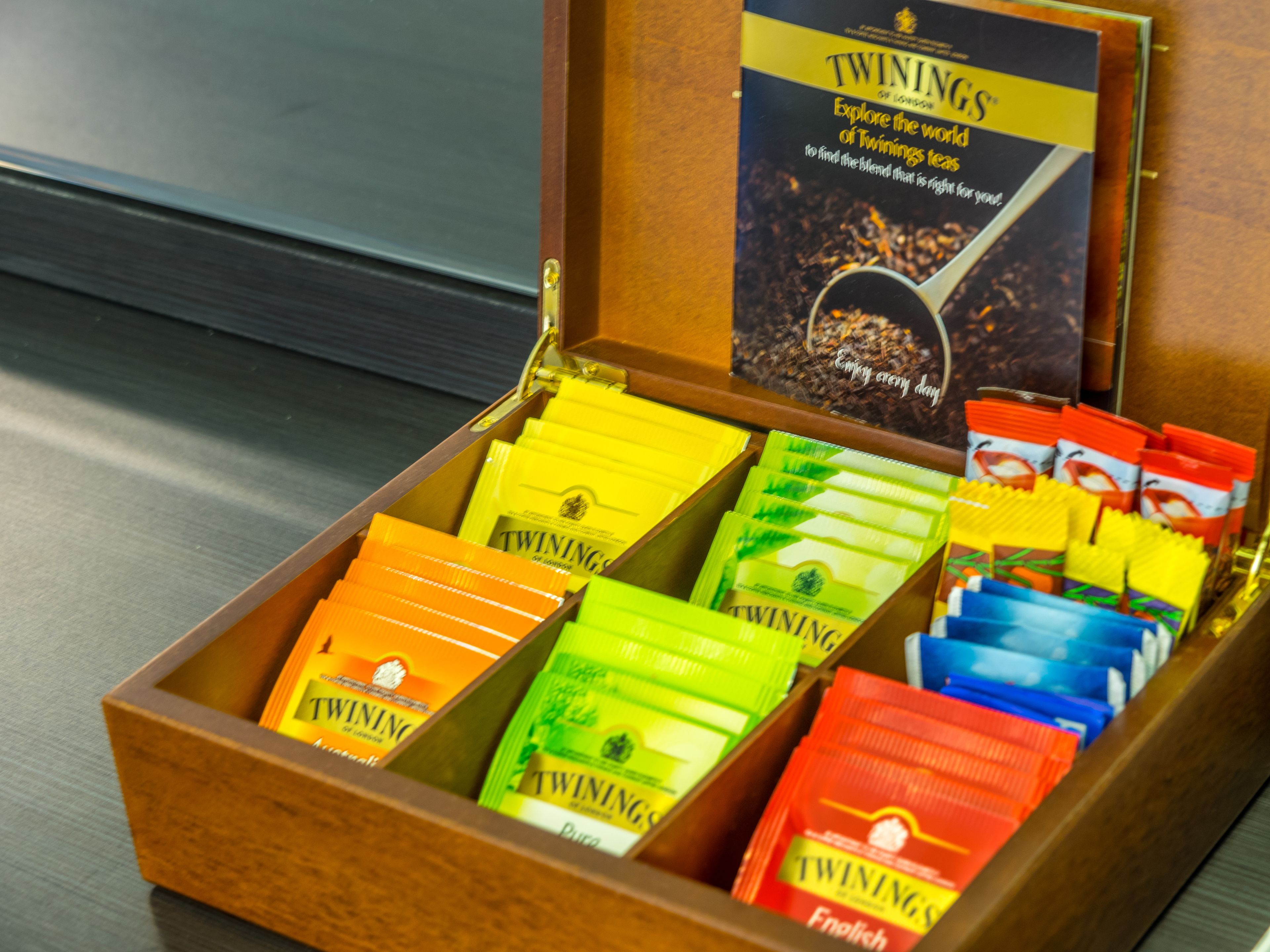 A wooden box containing various Twinings tea packets.