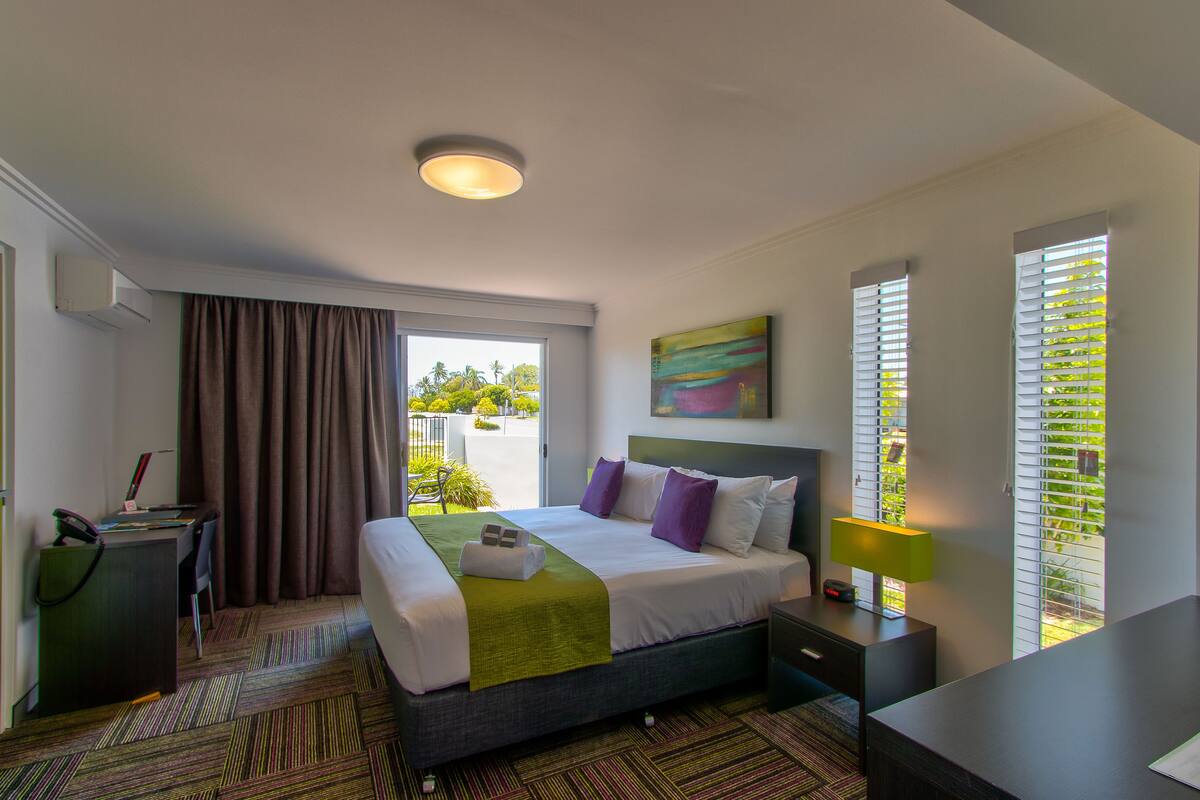 Ein Hotelzimmer mit Bett, Schreibtisch und Blick auf Grün.