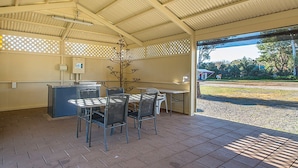 Ein überdachter Patio-Bereich mit Tisch und Stühlen, einer kleinen Theke und Blick ins Freie.