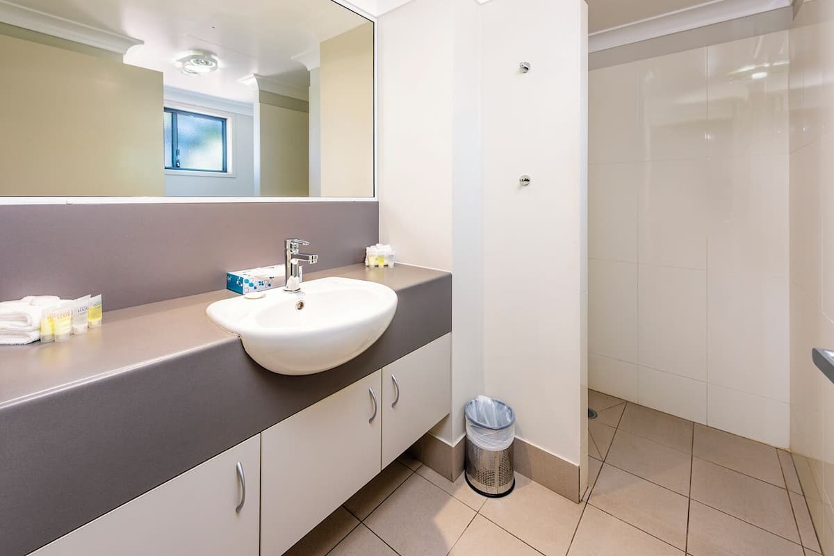 Un baño moderno con lavamanos blanco, encimera gris y un espejo grande.