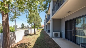 Een modern gebouw met een overdekt buitenverblijf, airconditioning en een pad omzoomd met bomen.