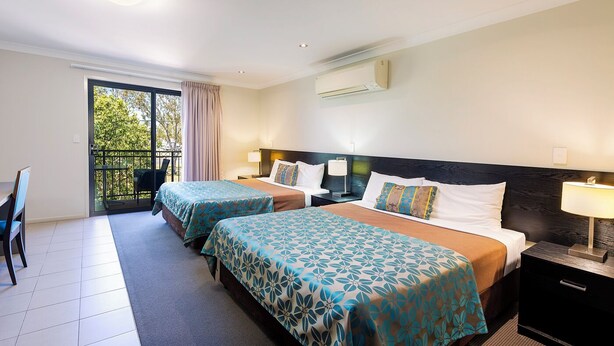 Een hotelkamer met twee bedden, een balkon, een eethoek en een airconditioning.