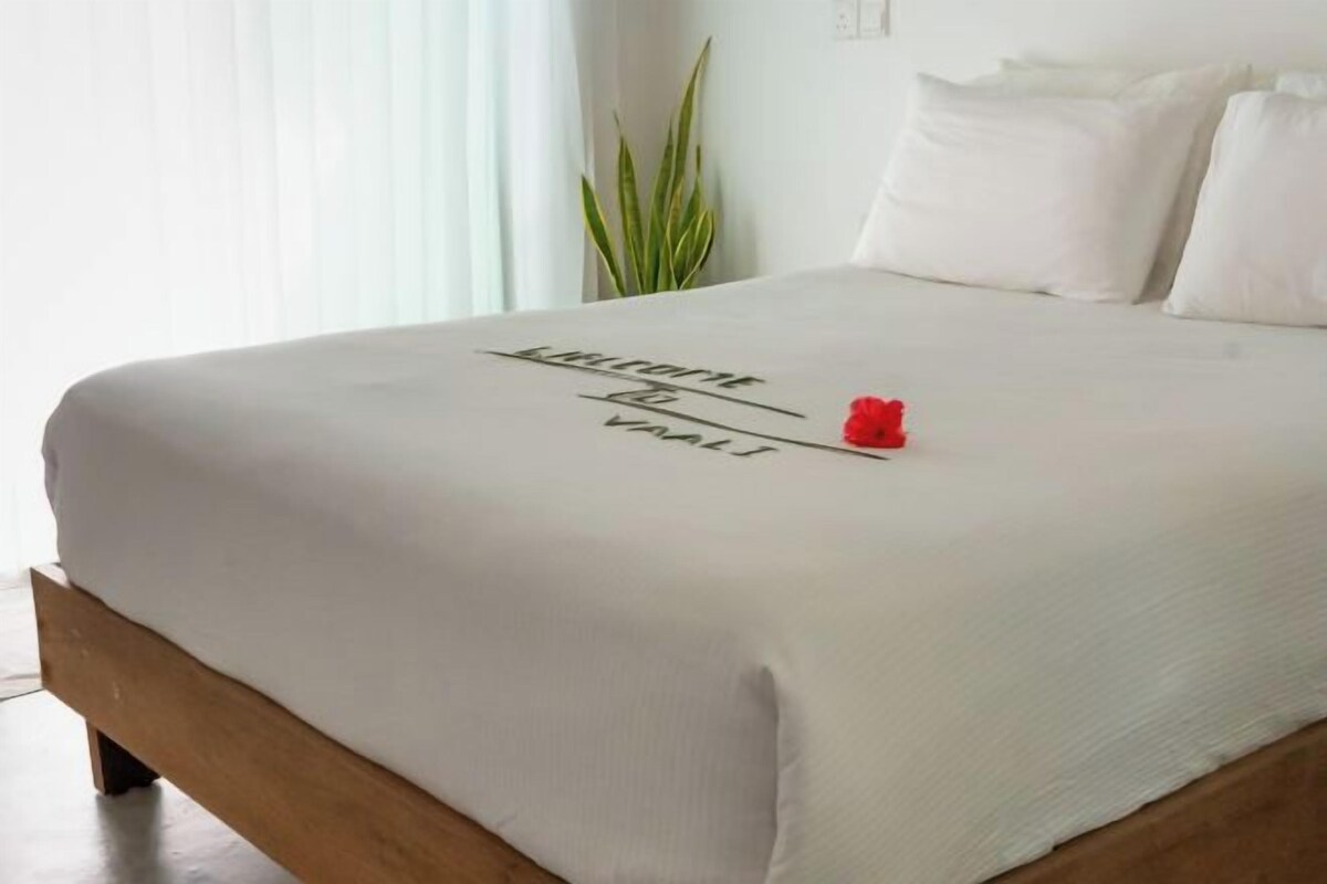 A neatly made bed with a white bedspread and a red flower decoration.