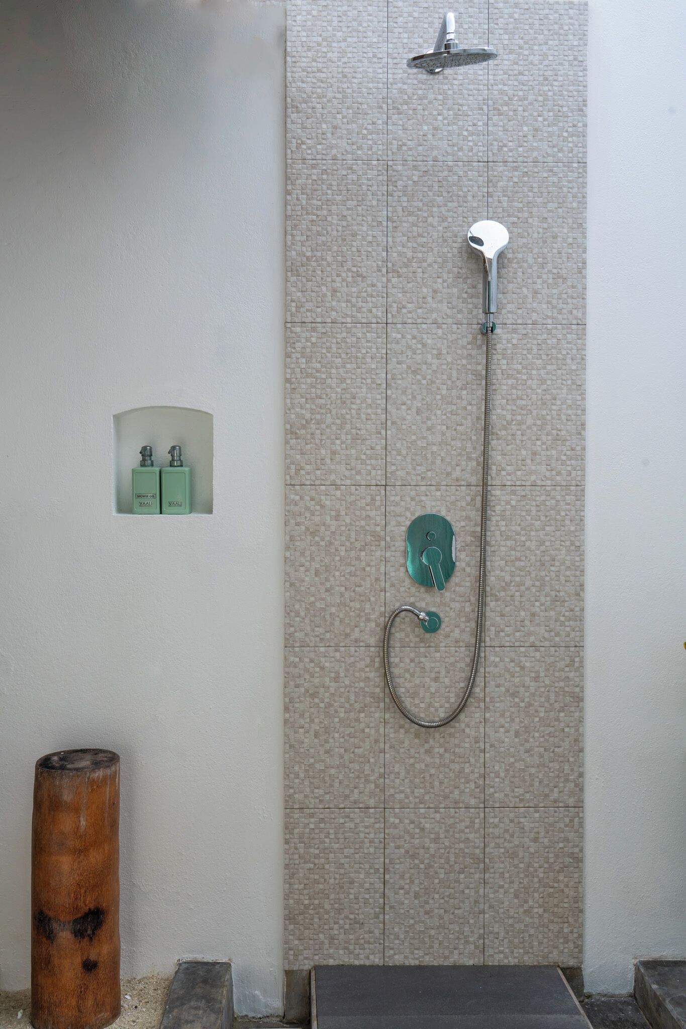 A shower with a handheld showerhead and a wall-mounted control panel.