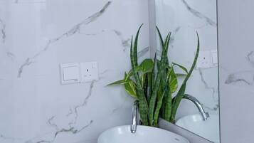 A bathroom with a white marble sink, a mirror, and a potted plant.