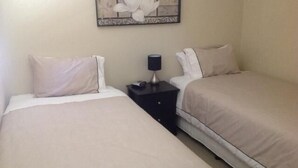 A hotel room with two beds, a nightstand with a lamp, and a wall-mounted artwork. - Breakaway Apartments (Cowra)