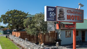 A motel with a sign indicating it is vacant, a stone wall, and a fence. - Gladstone Motel Nelson (Richmond)