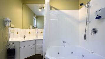 A bathroom with a white bathtub, a shower, a sink, and a hairdryer.