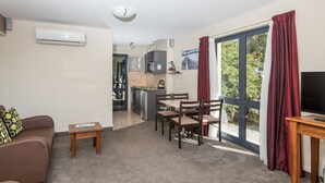 A compact living space with a kitchenette, a dining area, and a sofa. - Gladstone Motel Nelson (Richmond)