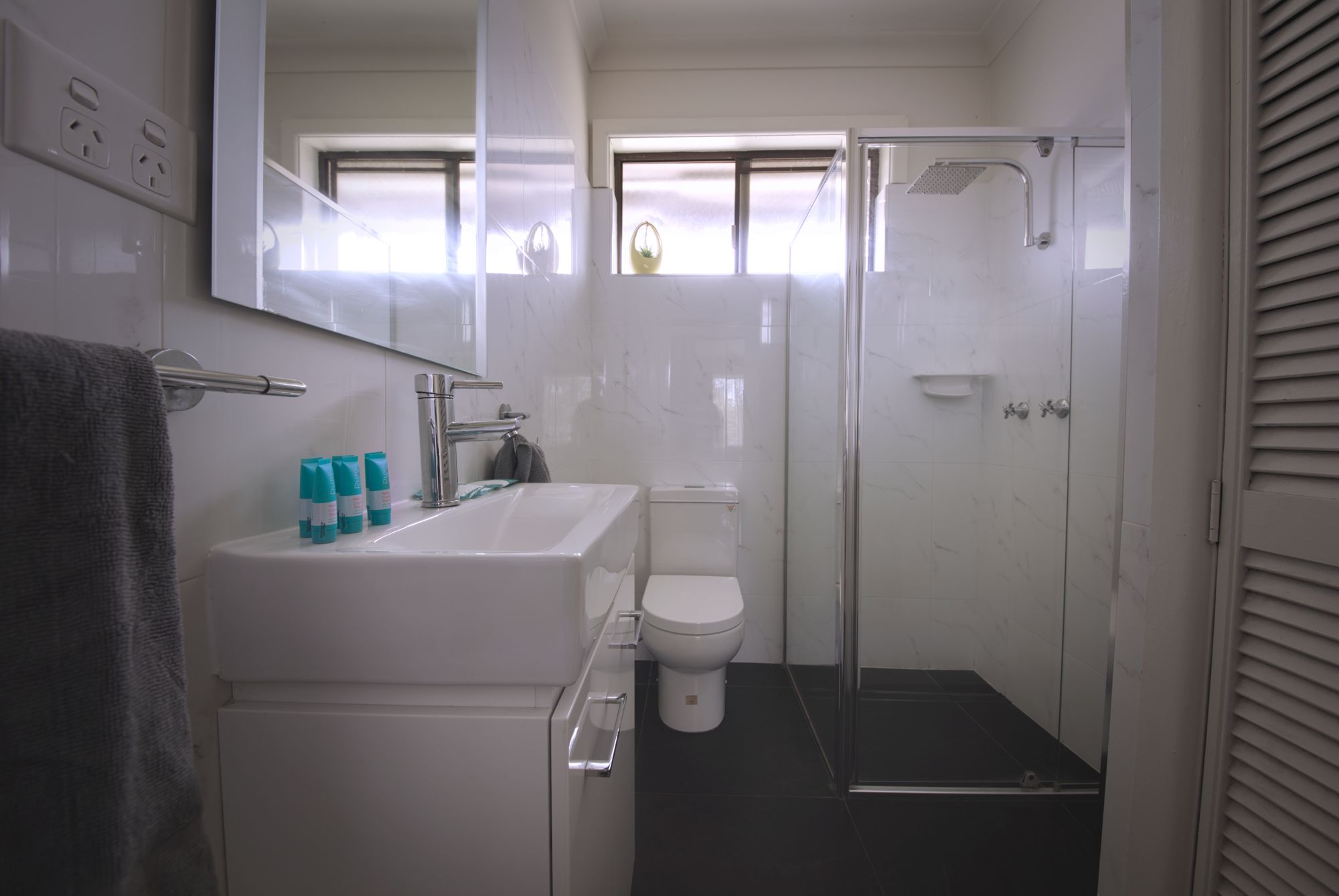 A modern bathroom with a white sink, toilet, and glass shower enclosure.